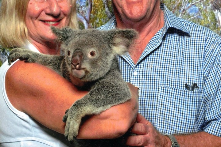 a man holding a teddy bear posing for the camera