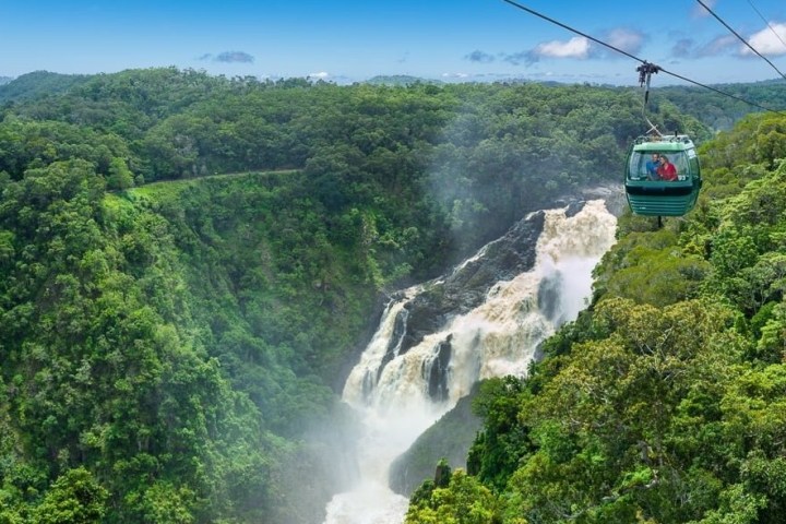 a train traveling down train tracks near a forest with Devon Falls in the background