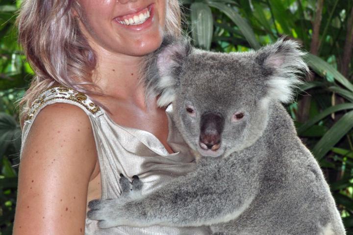 a woman sitting in front of a koala
