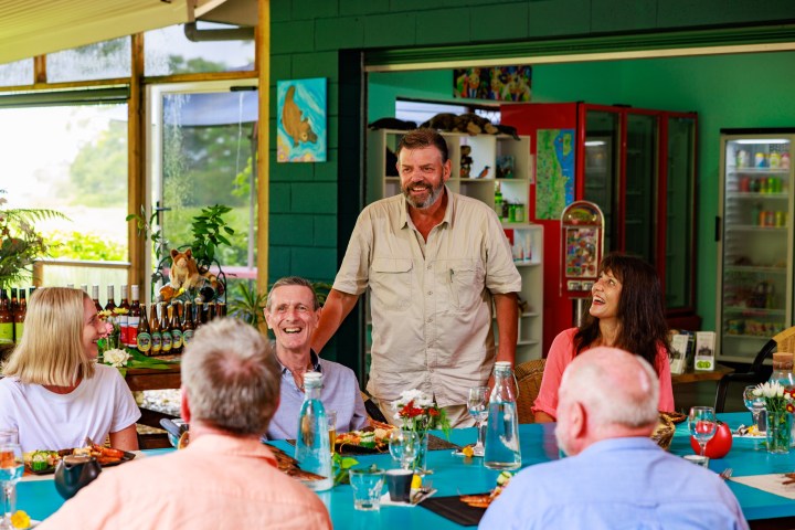 a group of people sitting at a table with a birthday cake