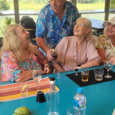 Group of cheerful people sharing a drink at a bright outdoor setting.